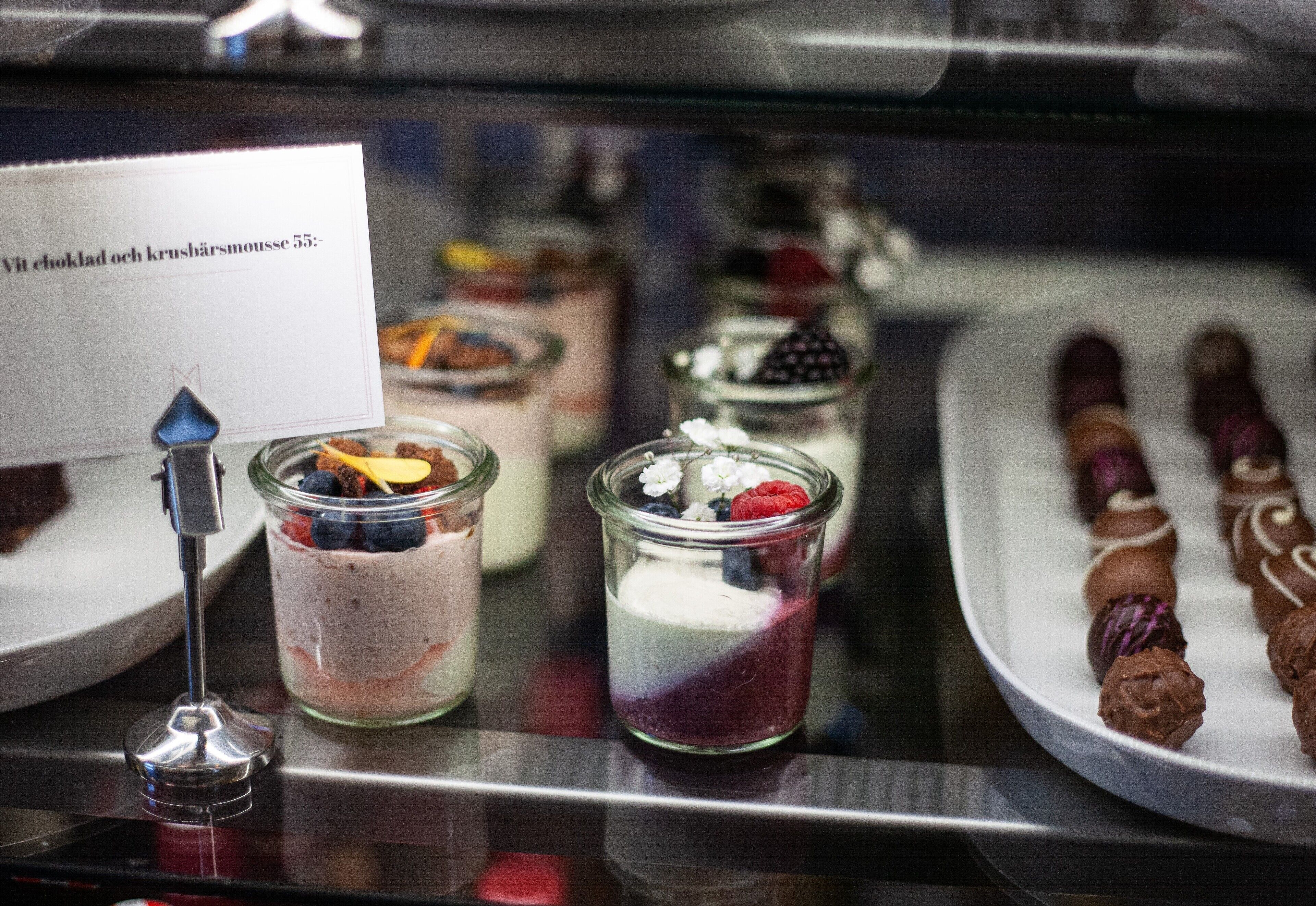 Una selección de postres, que incluye un dulce cubierto de chocolate y un postre en capas con frutos rojos.