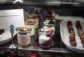 Una selección de postres, que incluye un dulce cubierto de chocolate y un postre en capas con frutos rojos.