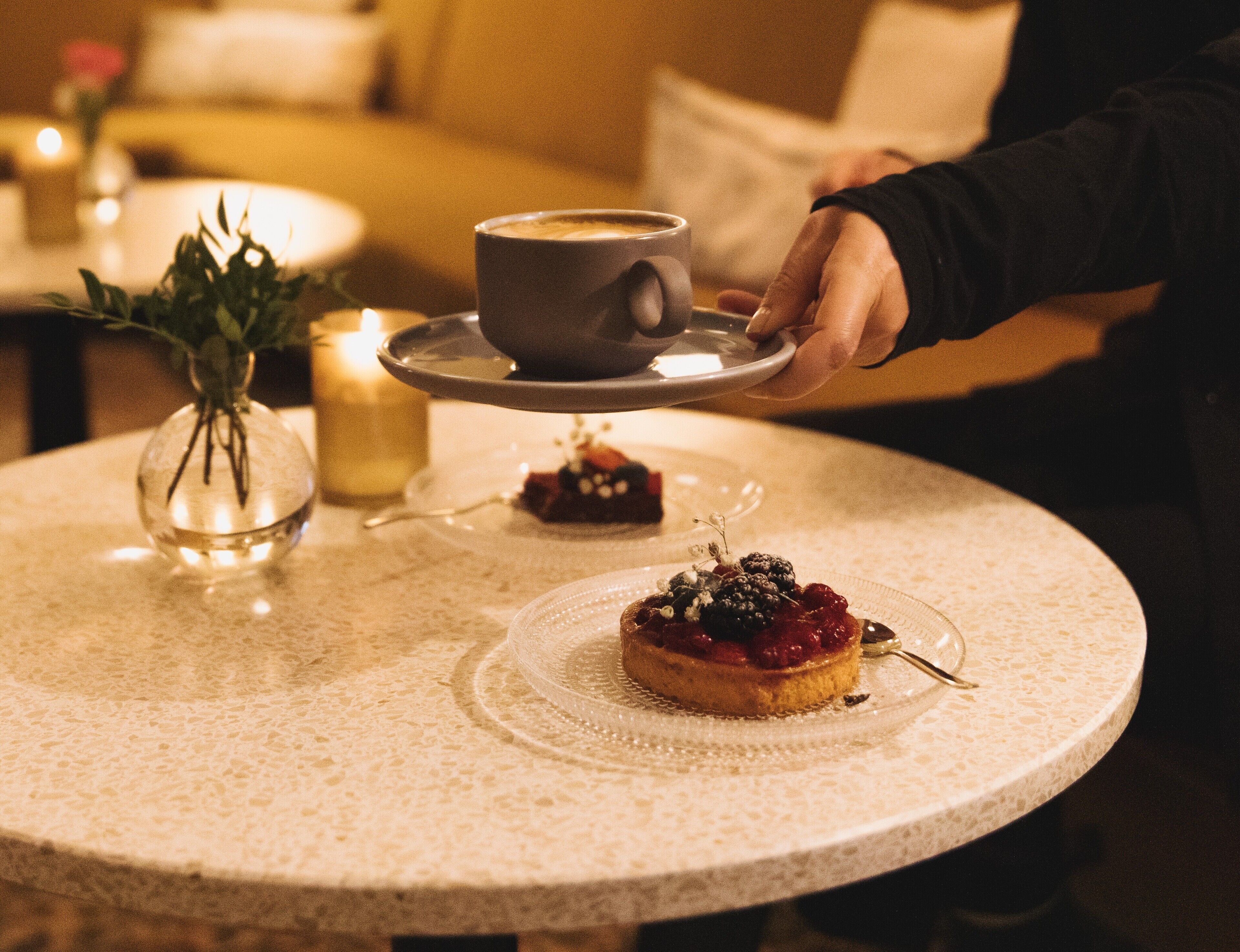 A round table with a dessert and a cup of coffee.