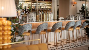 A bar area with multiple stools, a bar counter, and a variety of bottles and glasses. - Elite Hotel Mårtenson (Halmstad)