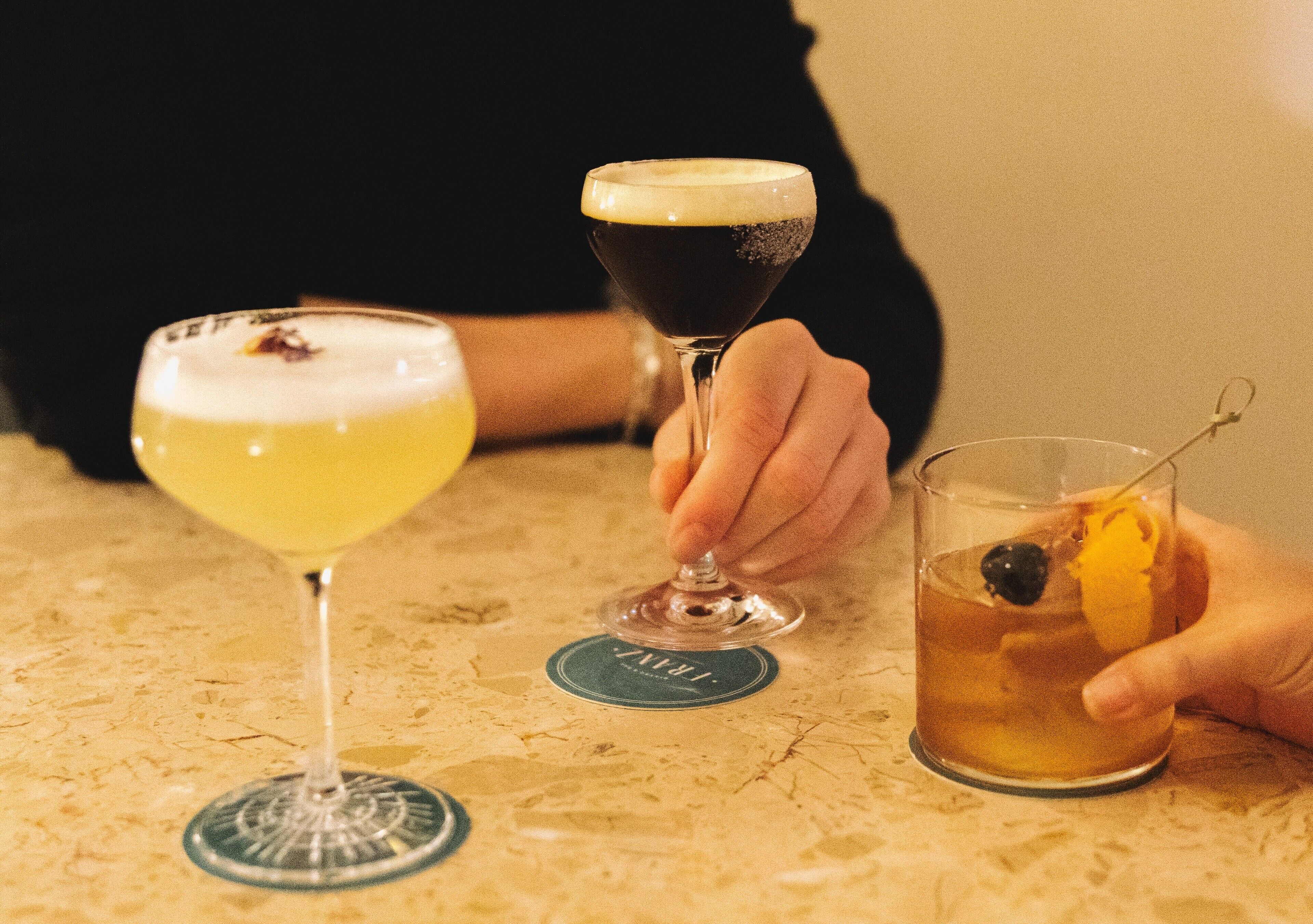 Three glasses of different beverages on a table with a coaster.