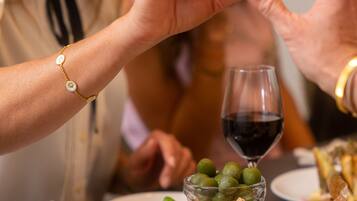 A dining table with a variety of food items including bread, cheese, olives, and a glass of red wine.