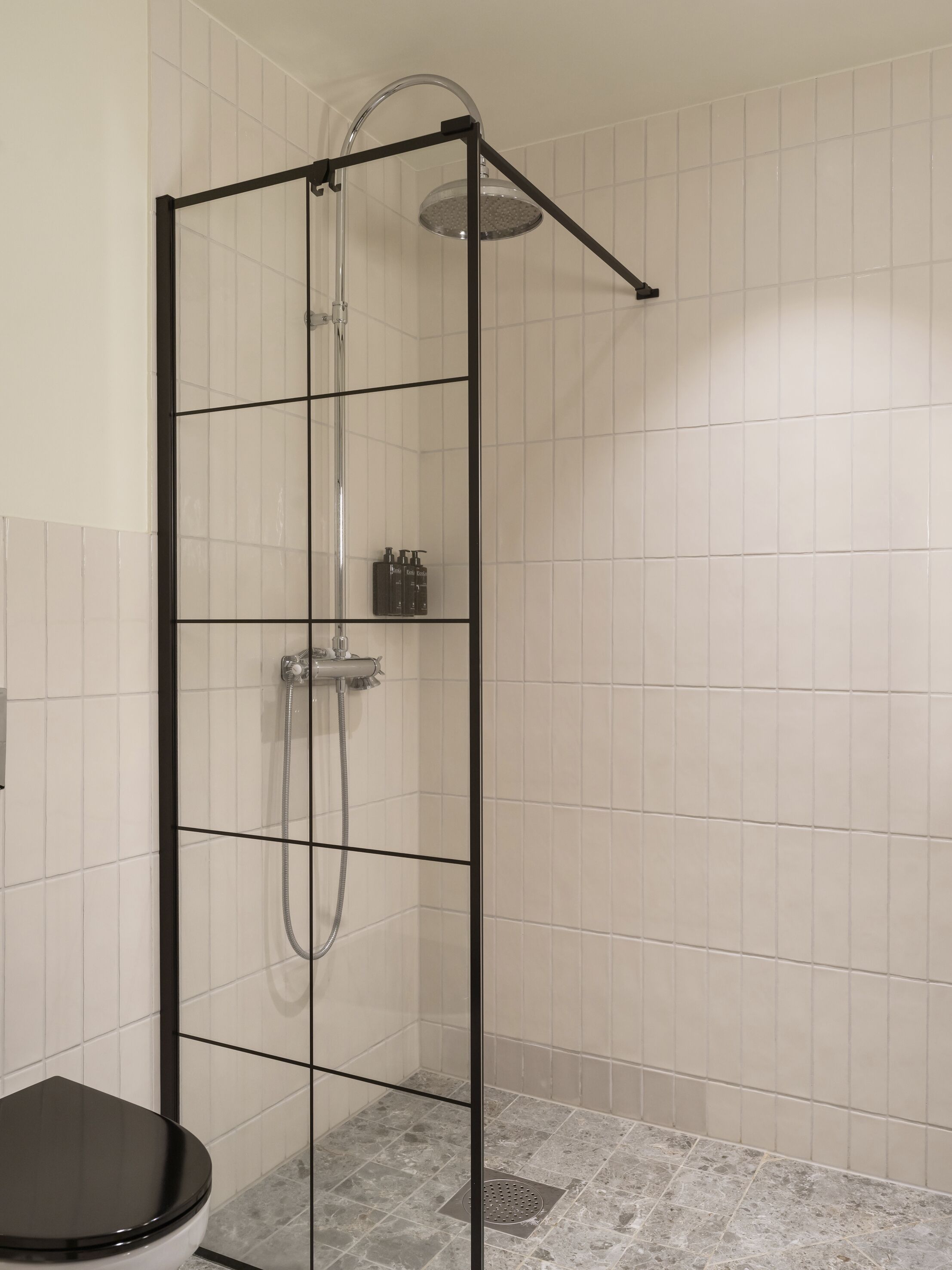 A modern bathroom with a glass-enclosed shower, a toilet, and a tiled floor.