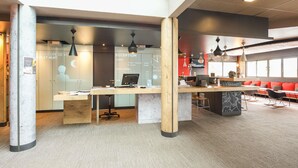 A modern office space with a reception desk, computer, and seating area. - ibis Pau Lescar (Lescar)