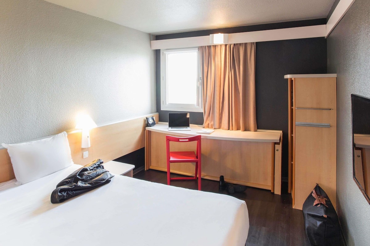Hotellihuone, jossa on sänky, työpöytä, tuoli ja vaatekaappi.