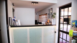 Un área de recepción con mostrador, puertas de cristal y una ventana con persianas.