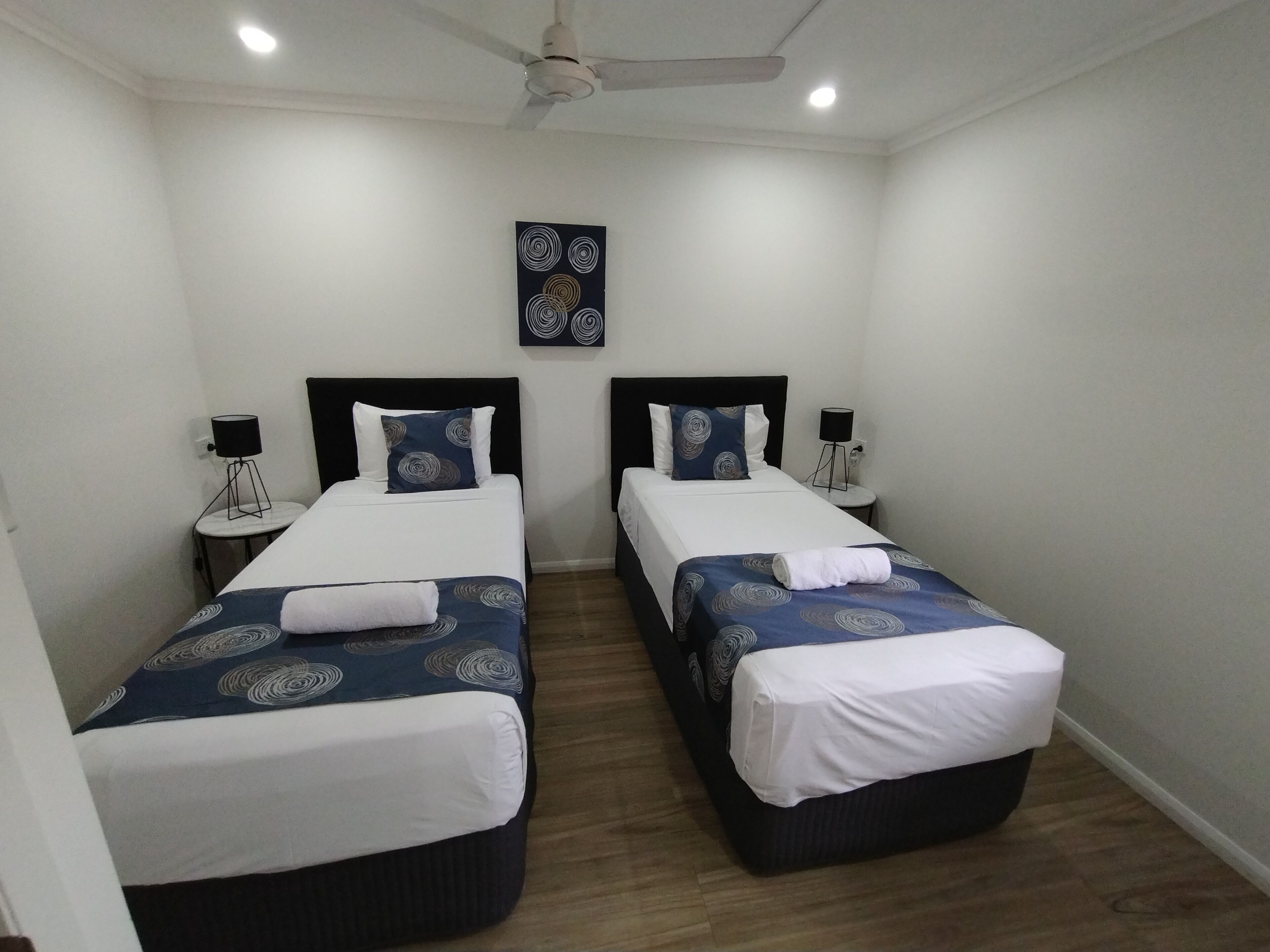 A twin room with two single beds, each with a headboard, bedside tables, and lamps.
