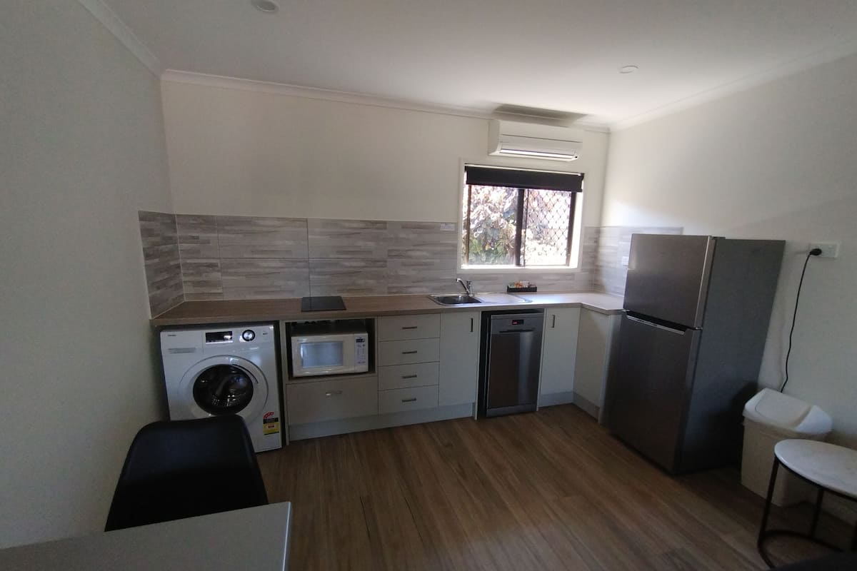 A compact kitchen with a washing machine, microwave, dishwasher, and refrigerator.