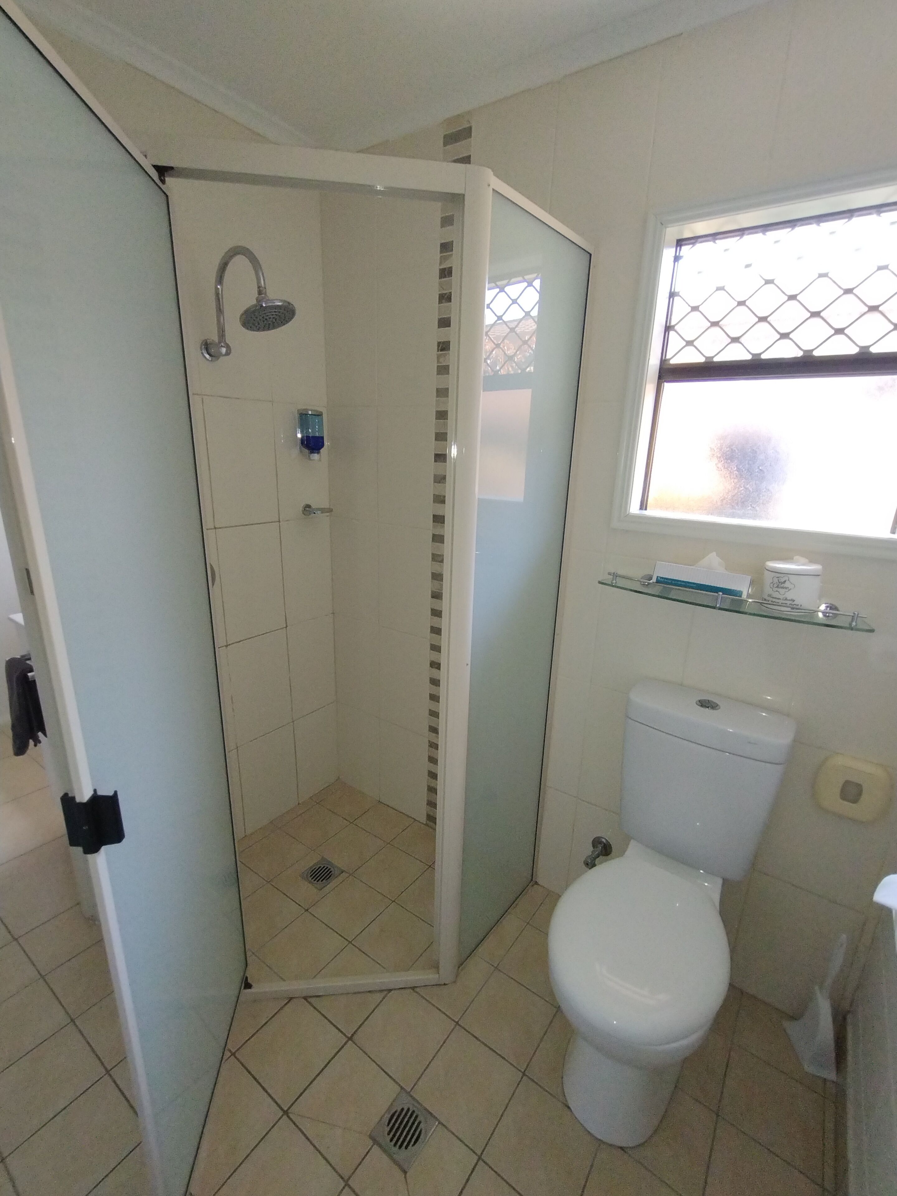 Un baño con ducha, inodoro y ventana.