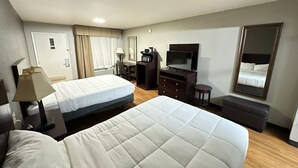 A hotel room with two beds, a desk, a TV, a mirror, and a wardrobe.