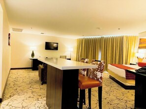 A hotel room with a dining area, a bed, and a TV.