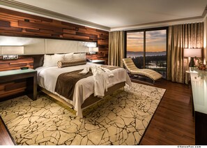 Une chambre d’hôtel moderne dotée d’un grand lit, d’une chaise longue, d’une vue sur le paysage urbain et d’un mur décoratif en bois.