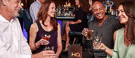 A group of people seated at a bar area with a visible 'HQ' sign, suggesting a central location or meeting point.