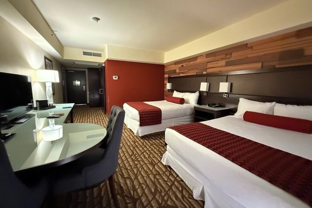 Ein Hotelzimmer mit zwei Betten, einem Schreibtisch und einem Stuhl.