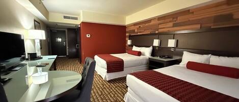 A hotel room with two beds, a desk, and a chair.