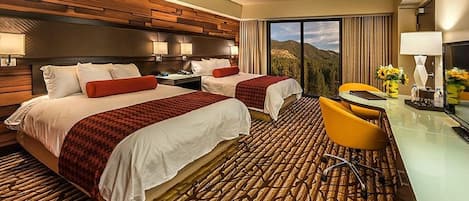 A hotel room with two beds, a desk, and a chair.