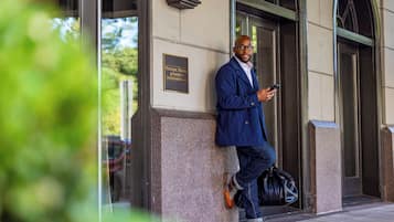 Un hombre apoyado en un edificio con un letrero que dice "Historic Hotels of America".