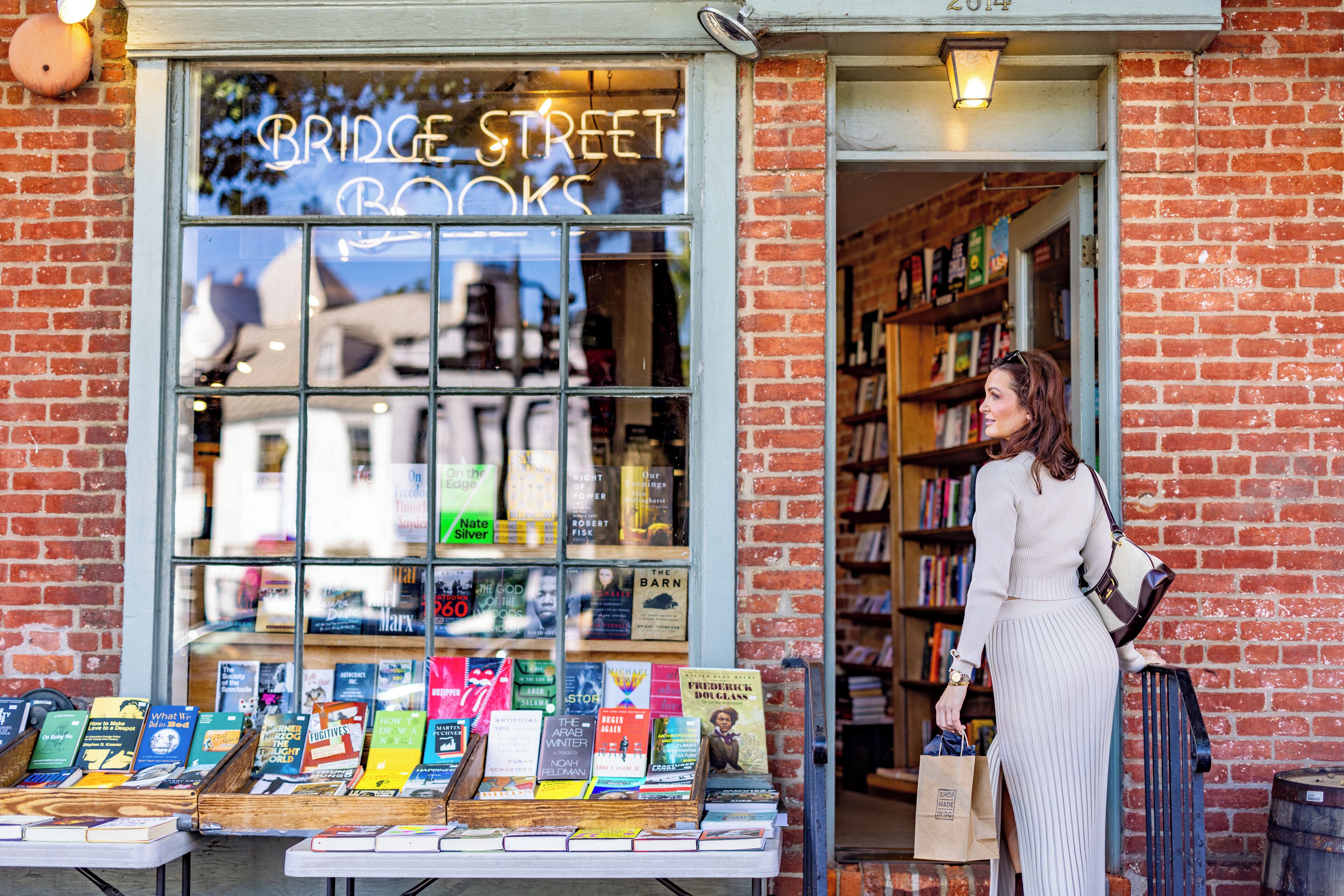 Une librairie à la façade en briques et à l’enseigne lumineuse qui indique « Bridge Street Books ».