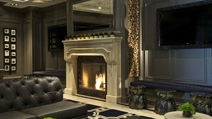 Una sala de estar moderna con chimenea, un sofá de cuero negro, jarrones decorativos y un televisor de pantalla plana montado en la pared.