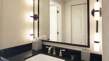 Un baño con un espejo grande, dos lavamanos y apliques de pared.