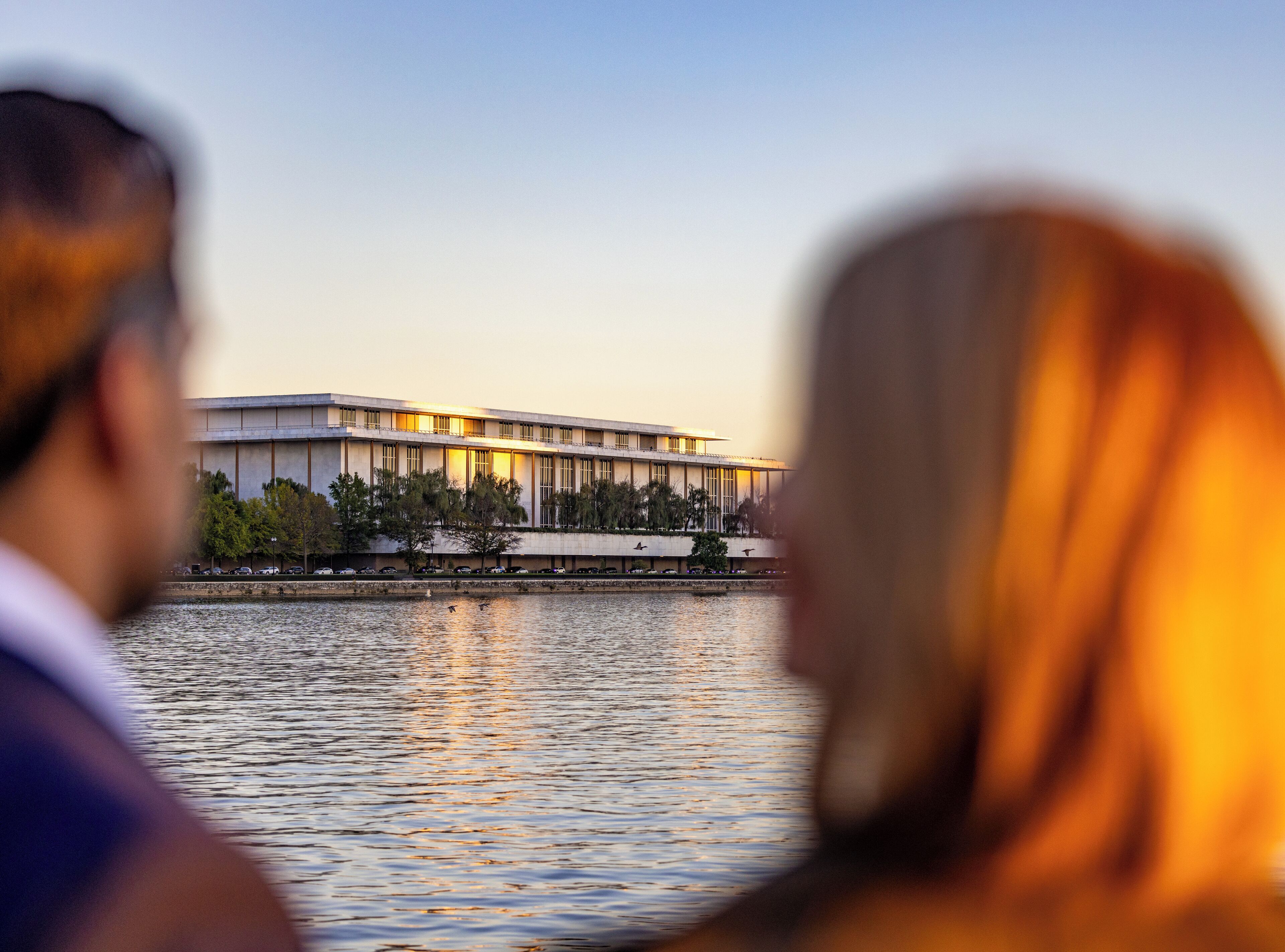 Een modern gebouw met een plat dak en grote ramen, gelegen aan een waterpartij.
