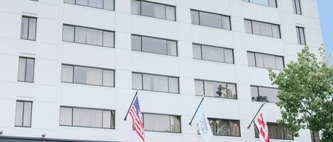 A multi-story hotel with a modern facade, featuring a prominent entrance with an awning and outdoor seating area.