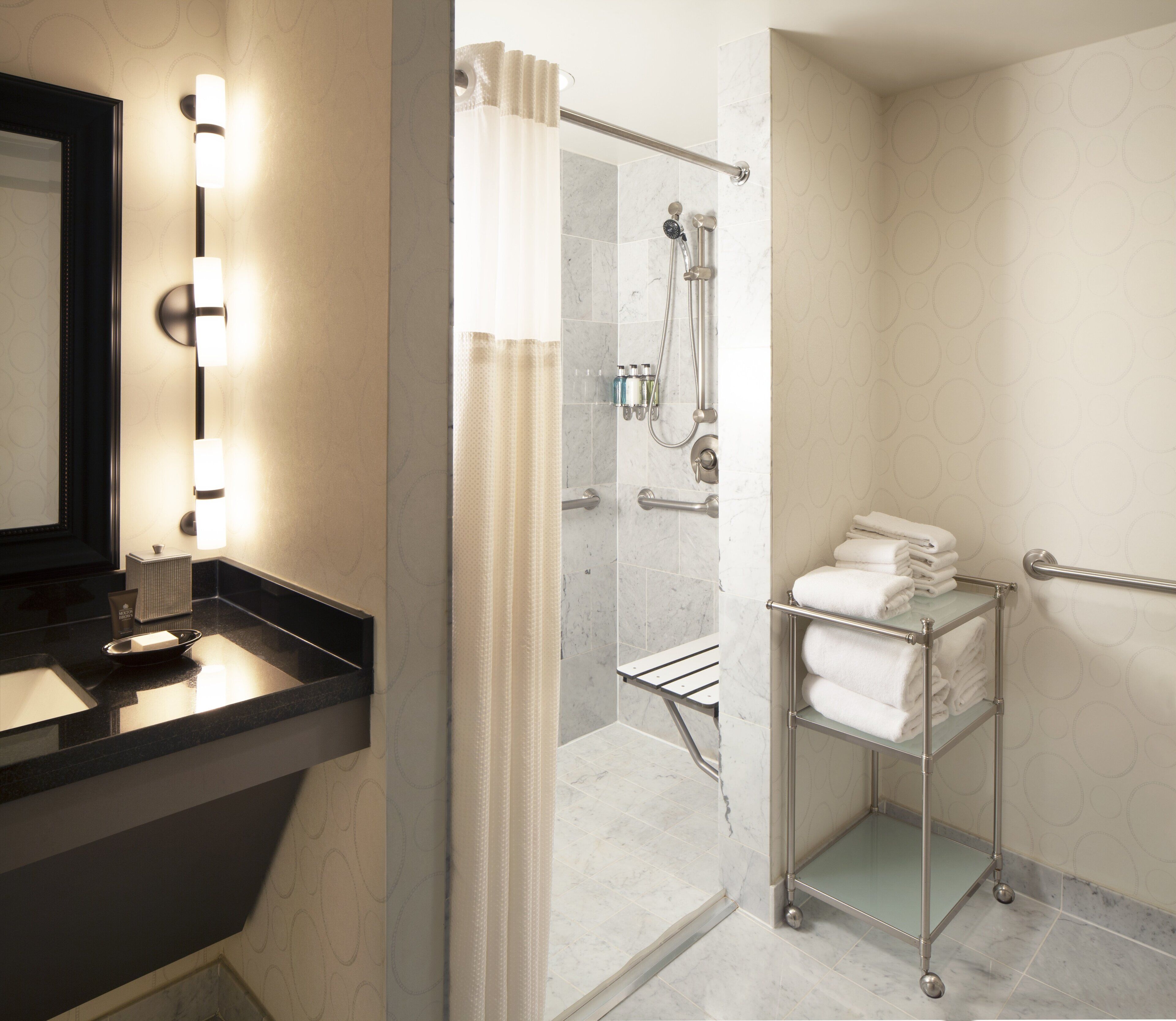 Une salle de bain moderne avec un meuble-lavabo, une douche dotée d’une porte en verre et un porte-serviettes.