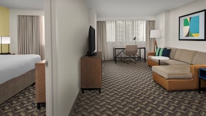 Ein Hotelzimmer mit Bett, Schreibtisch, Sofa und Fernseher.