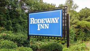 Ein Schild für Rodeway Inn, umgeben von üppiger Vegetation.