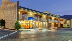 Ein Motel mit einer zentralen Eingangspforte, mehreren Balkonen und einem Parkplatz.