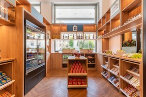 Una tienda bien organizada con estantes llenos de diversos productos, un expositor refrigerado y una vista despejada a la calle.