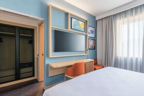 A hotel room with a bed, a desk, a chair, a TV, and a wardrobe. - Hilton Garden Inn Rome Colosseum (Rome)
