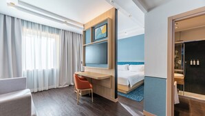 A hotel room with a bed, a desk, a chair, a TV, and a bathroom with a shower. - Hilton Garden Inn Rome Colosseum (Rome)