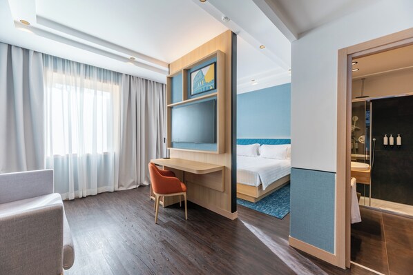 A hotel room with a bed, a desk, a chair, a TV, and a bathroom with a shower. - Hilton Garden Inn Rome Colosseum (Rome)