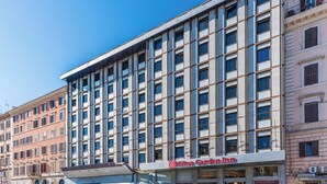 A modern hotel with a large glass facade, multiple floors, and a prominent Hilton Garden Inn sign. - Hilton Garden Inn Rome Colosseum (Rome)