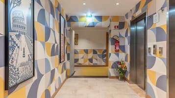 Un pasillo con paredes estampadas, un ascensor y un extintor.
