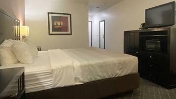 Une chambre d’hôtel avec un lit, une télévision, un bureau et un tableau encadré au mur.