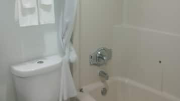 A bathroom with a toilet, a bathtub, and a shower curtain.