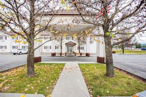 A building with a central entrance, flanked by trees with autumn leaves.