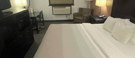 Une chambre d’hôtel équipée d’un lit, d’un bureau, d’une chaise, d’une télévision et d’une lampe.
