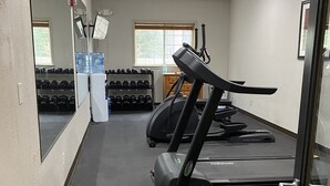 A gym with treadmills, dumbbells, and water coolers.