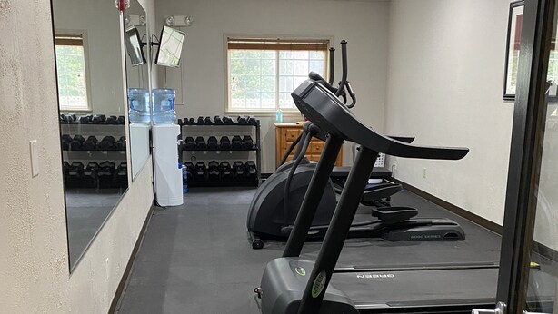 Un gimnasio con cintas de correr, pesas y dispensadores de agua.