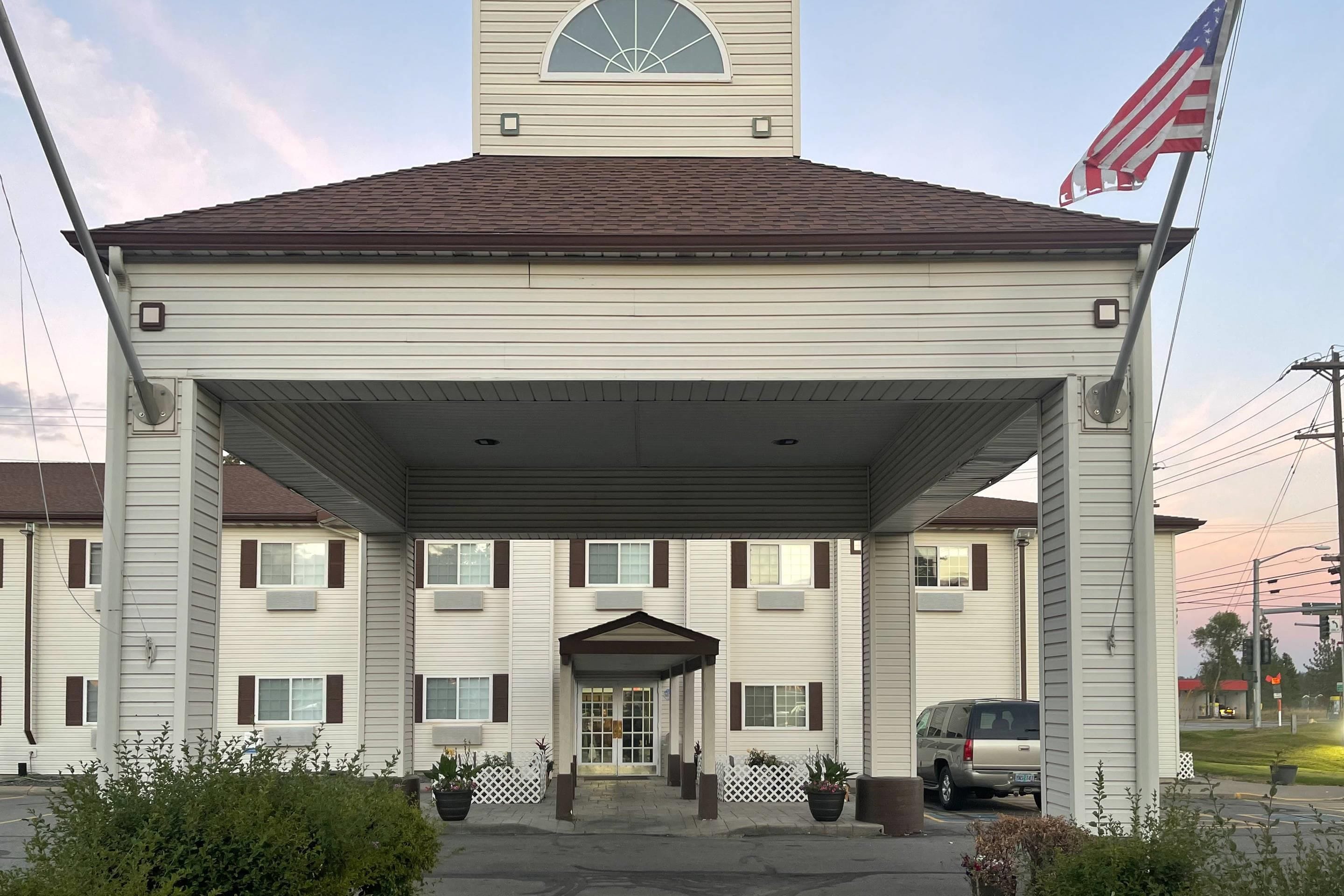 A two-story building with a covered entrance and a flagpole with an American flag.