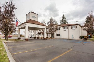 Un motel con edificio central, estacionamiento y una bandera.
