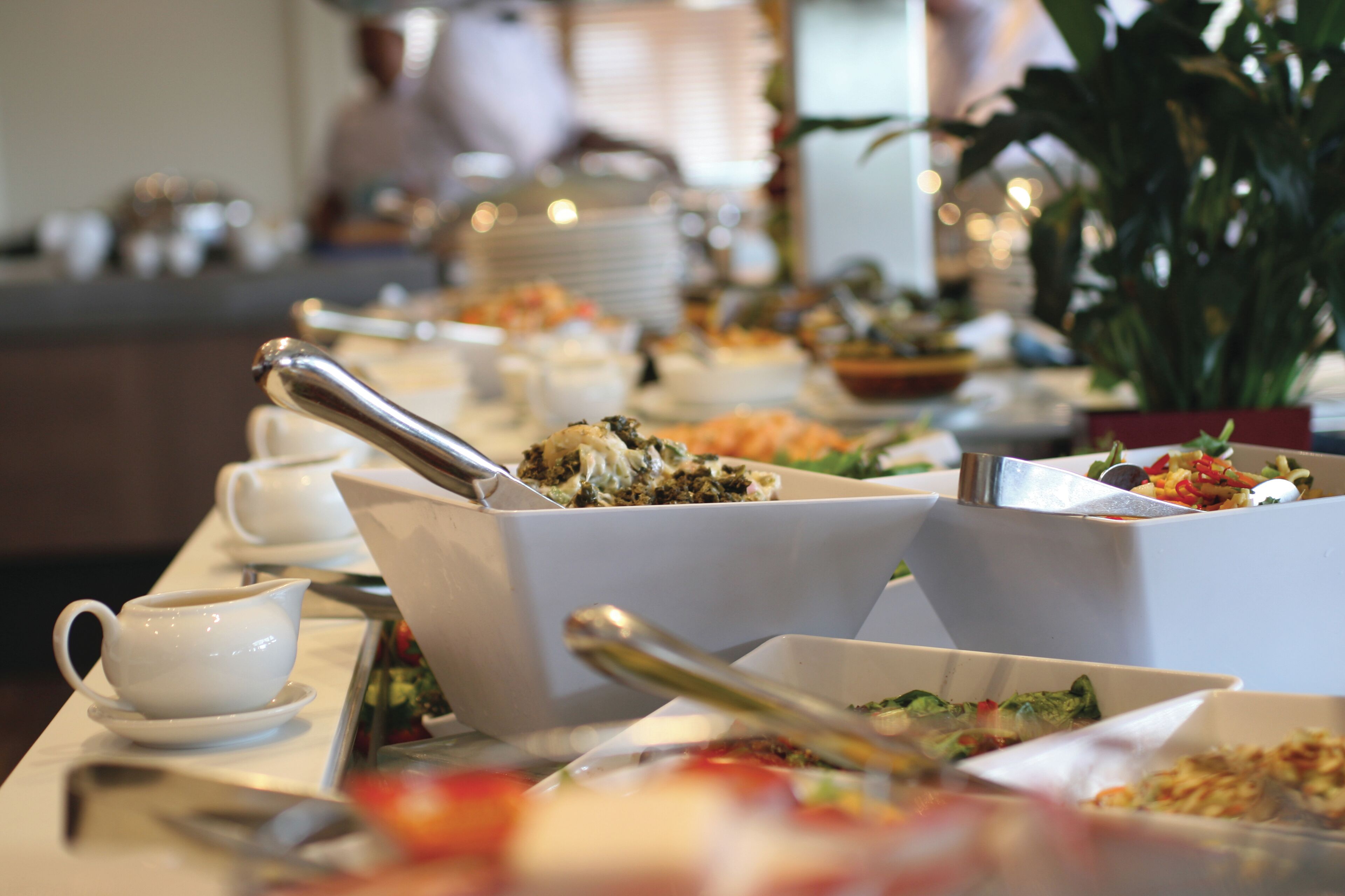 A buffet table with various dishes and serving utensils.