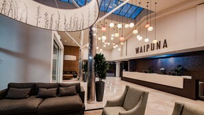 A modern lobby with a reception desk, seating area, and a large plant. - Waipuna Hotel & Conference Centre (Auckland)