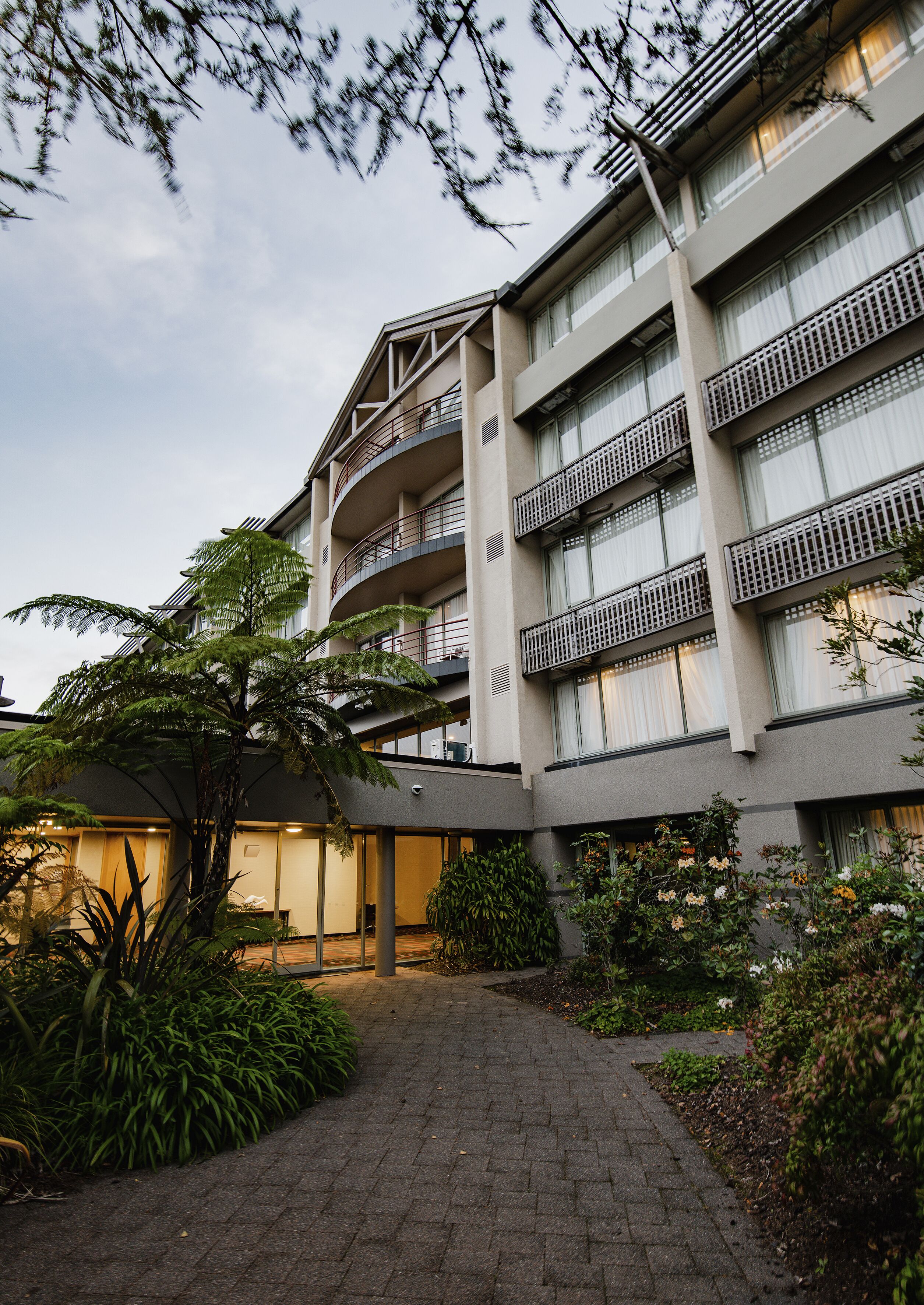 Un immeuble à plusieurs étages doté de balcons, d’une galerie couverte et entouré de verdure.