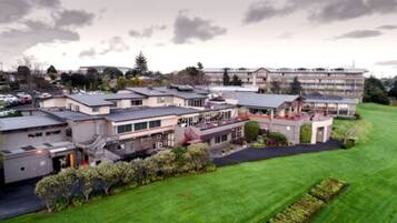 A modern hotel complex with multiple buildings, a well-maintained lawn, and a parking area.