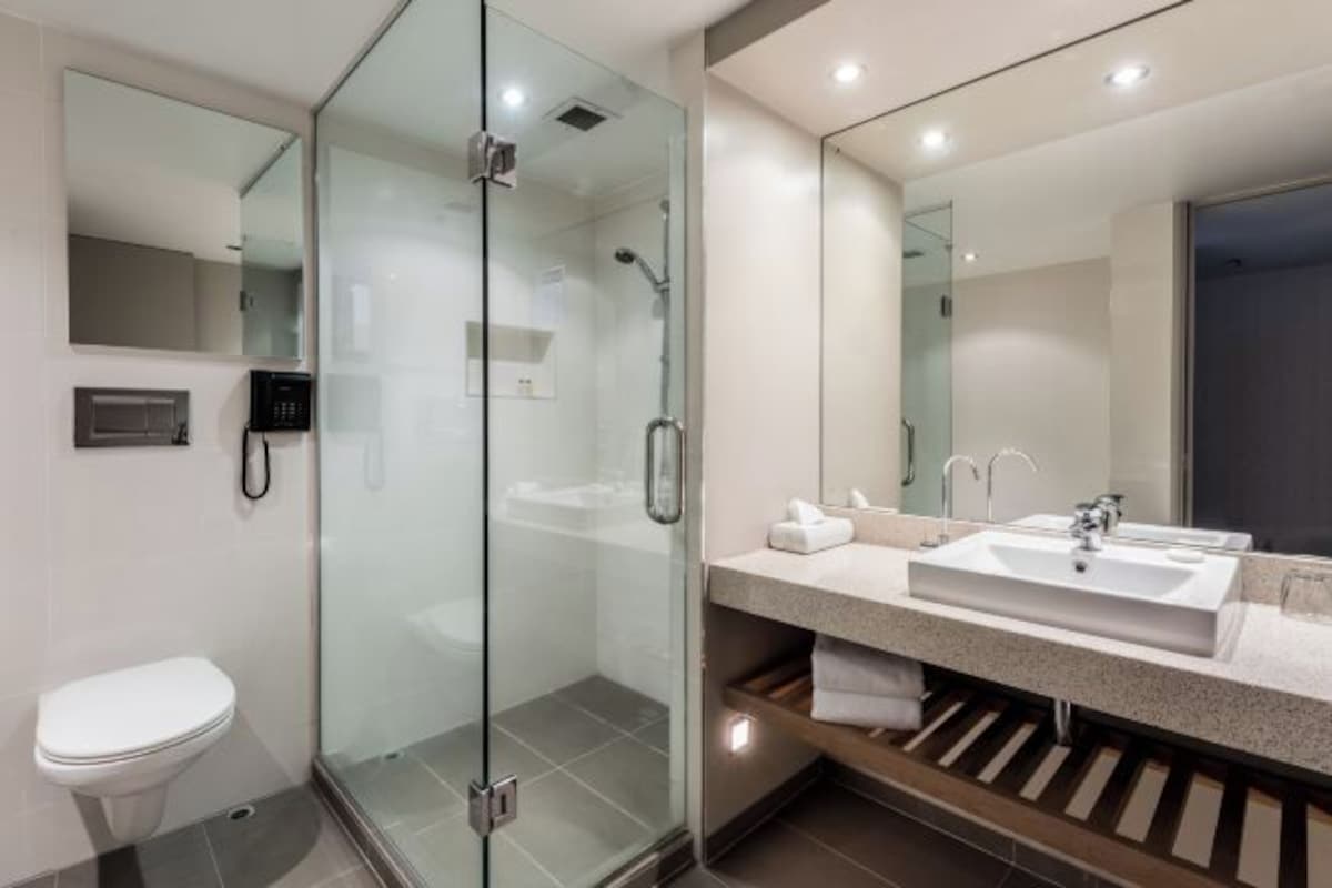 A modern bathroom with a glass-enclosed shower, a toilet, and a vanity with a sink and mirror.