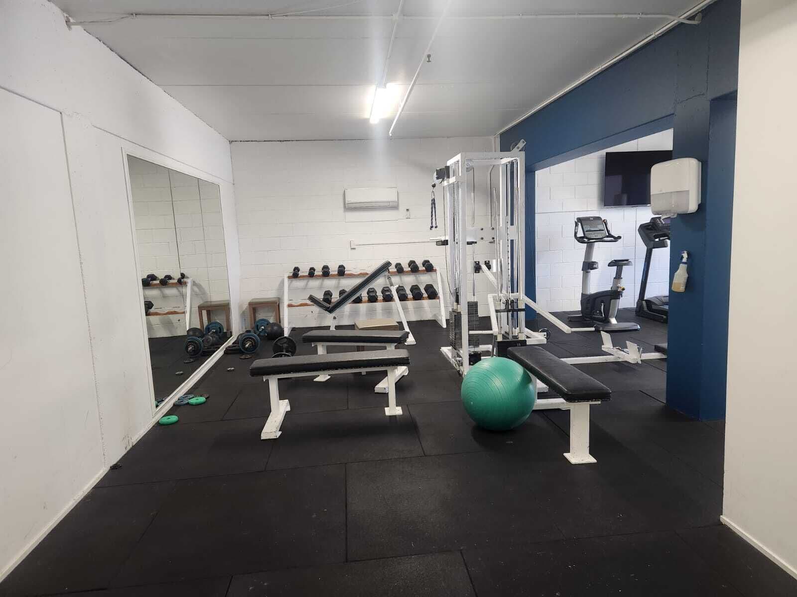 Une salle de sport équipée de matériel de musculation, de ballons d’exercice et de tapis de course.
